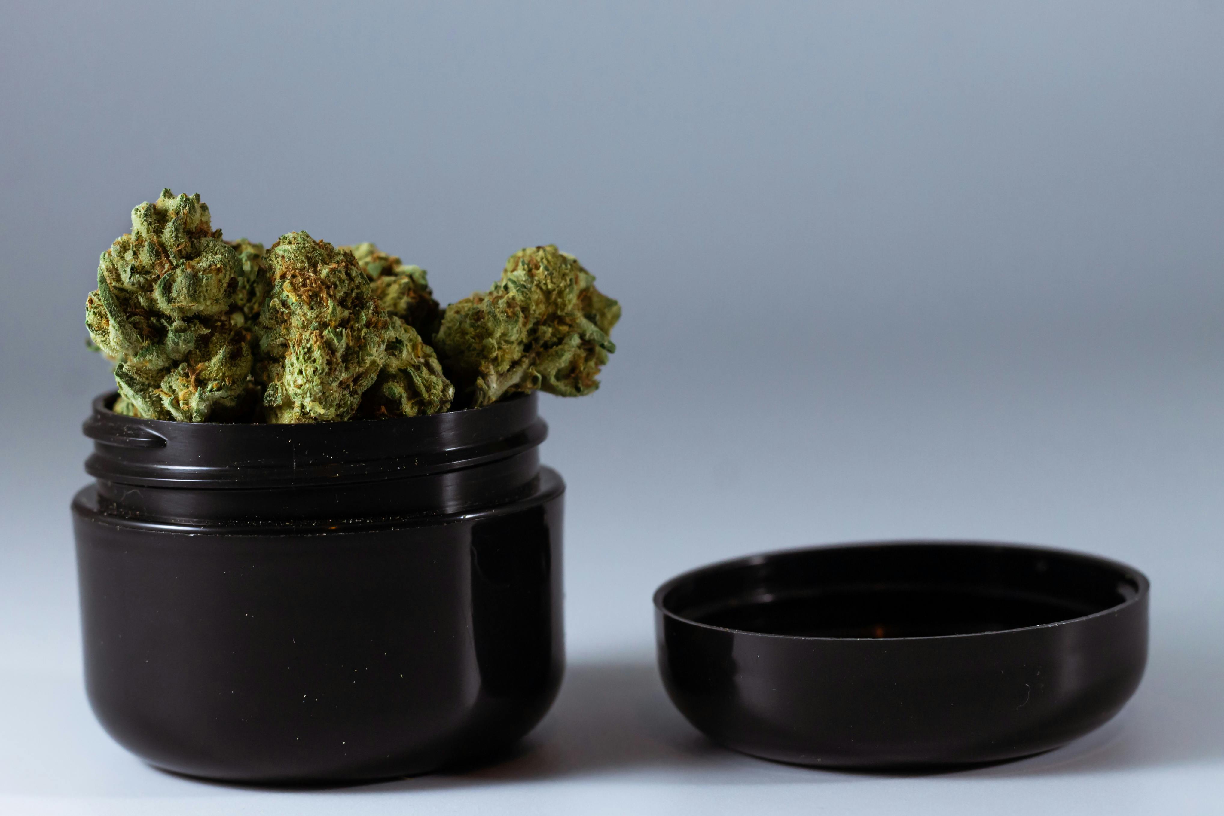 Cannabis buds in black jar container