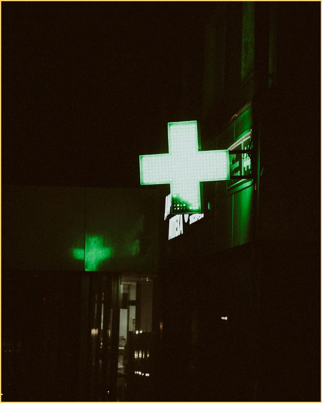 Green pharmacy cross sign at night