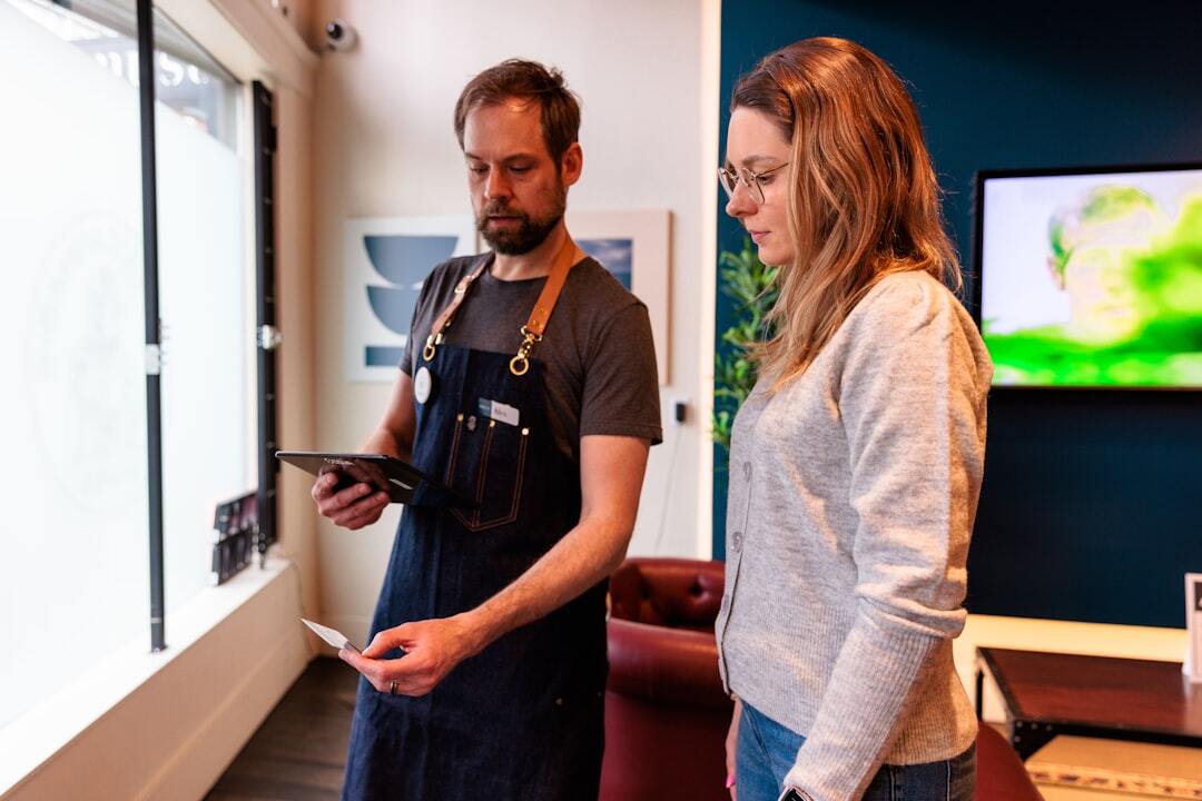 Shopkeeper assisting customer with payment tablet