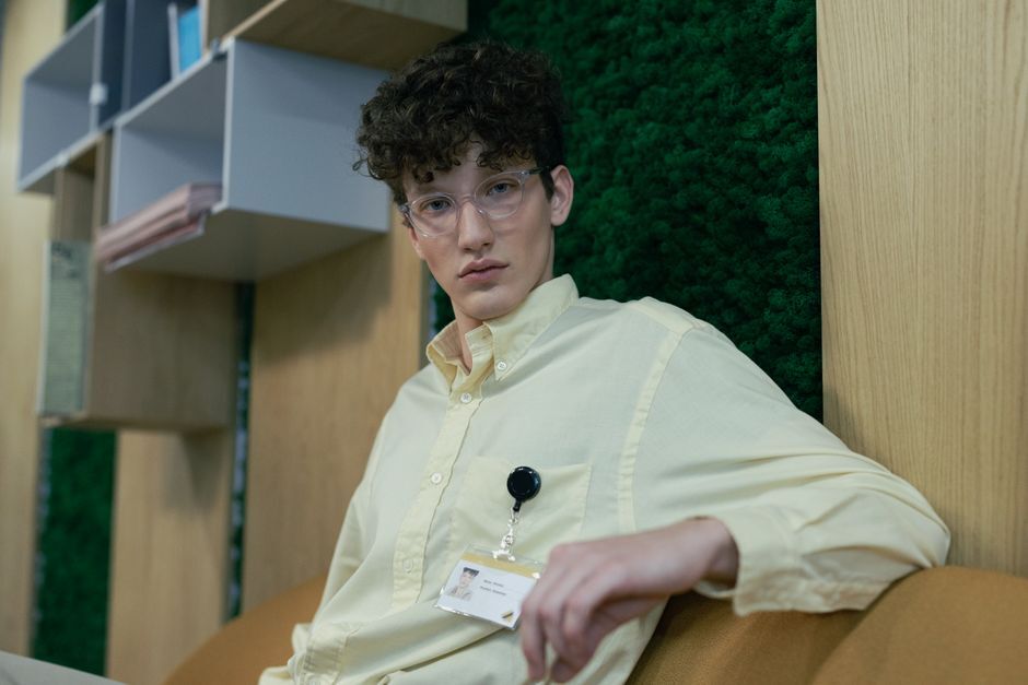 Man with glasses and badge sitting indoors